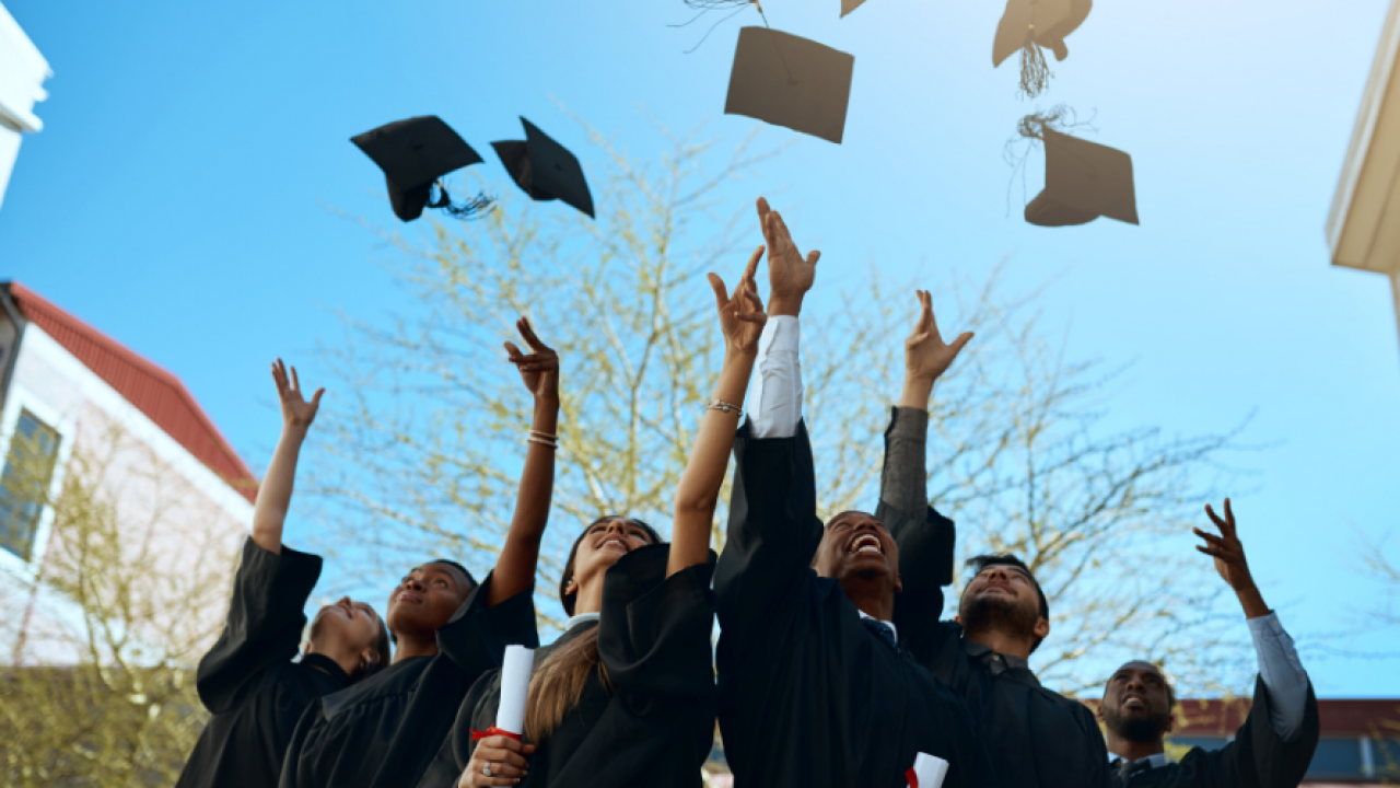 A graduating class throwing their caps in the air.