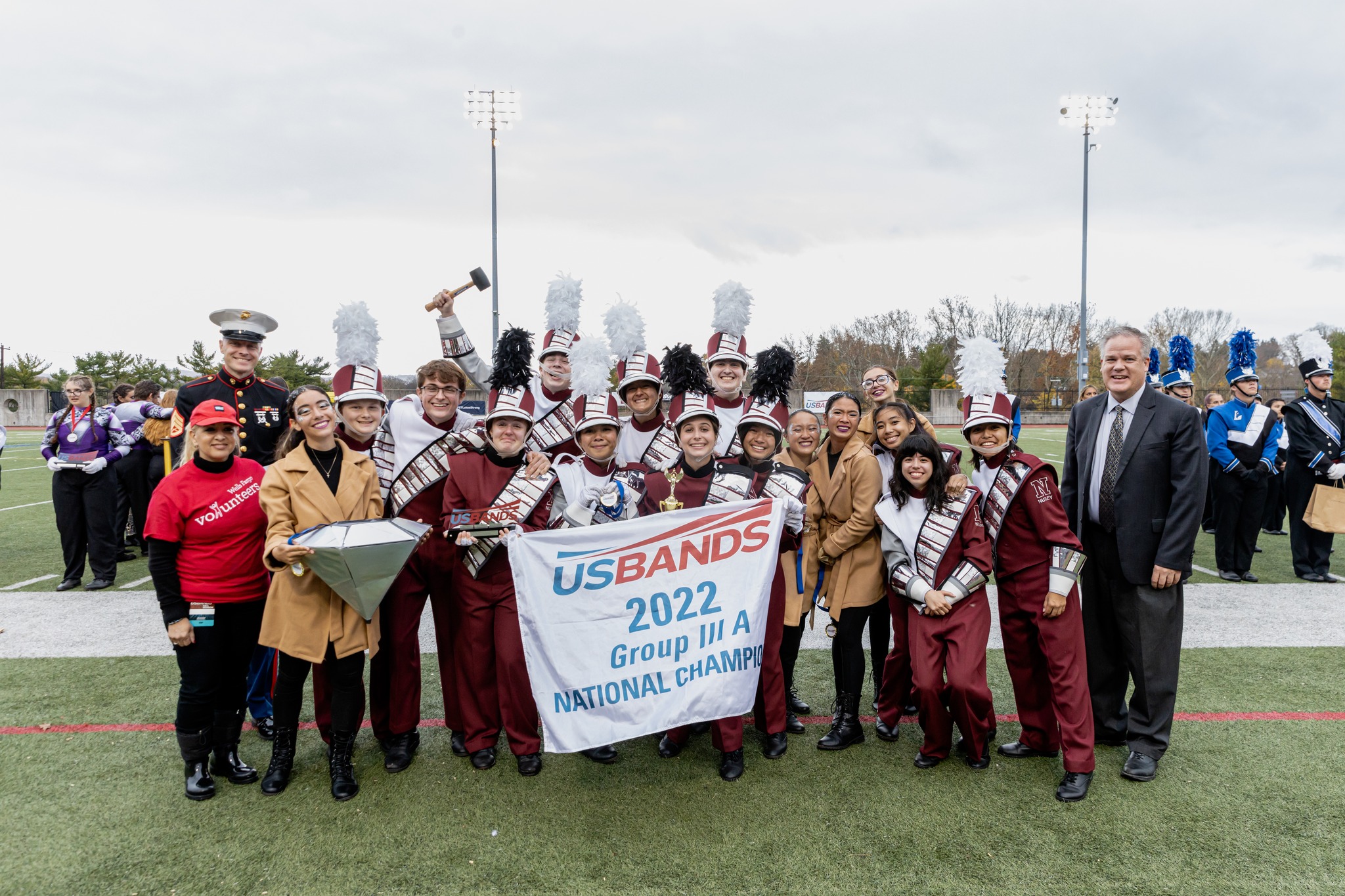 The NHS Marching Band smiling and holding a banner declaring them the USBands Group IIIA National Champions